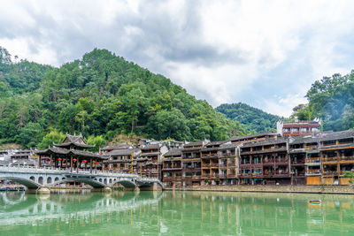 Buildings by lake against sky