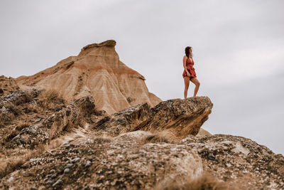 Low angle view of woman on rock against sky