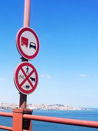 Road sign by sea against sky