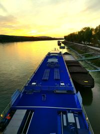 Boat moored on river against sky during sunset