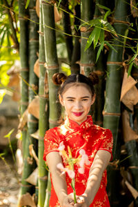 Midsection of woman standing against red plants