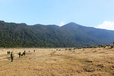 People on field by mountains against sky