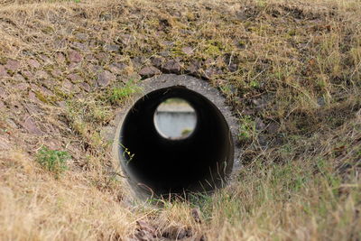 Abandoned car on field seen through hole