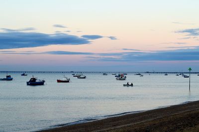 Boats in calm sea at sunset