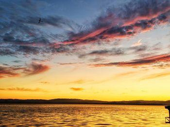 Scenic view of sea against dramatic sky during sunset