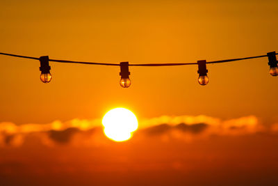 Close-up of light bulb against sky during sunrise 