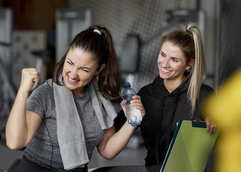 Smiling instructor looking at excited woman in gym