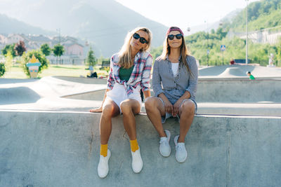 Portrait of two female friends sitting in a skatepark.