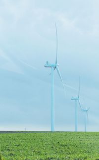 Wind turbines on field against sky