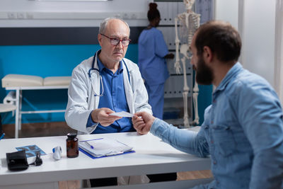 Doctor giving prescription to patient at clinic