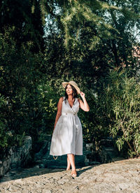 Full length portrait of woman standing against trees