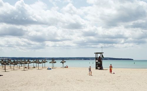 People playing on beach against sky