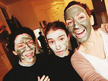Portrait of playful female friends with facial masks on their face while at home