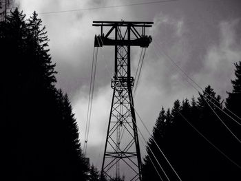 Low angle view of electricity pylon against cloudy sky