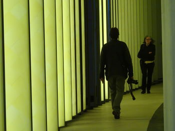 Rear view of people walking in corridor of building