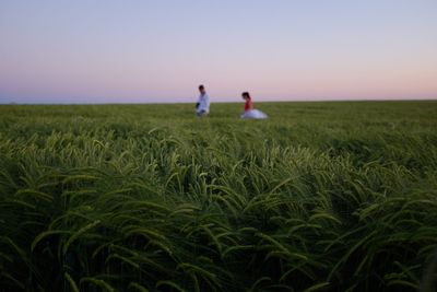 People standing in field against clear sky