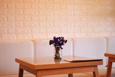 Flower vase on table against wall at home