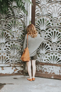 Rear view of woman standing against old gate