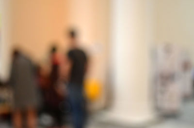 Defocused image of people standing against wall