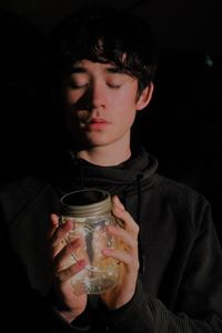 Man holding illuminated string lights in jar