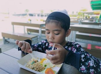 Boy holding ice cream on table in restaurant