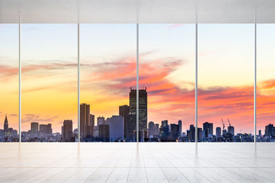 Modern buildings in city against sky during sunset