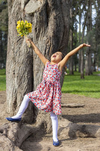Full length of girl with arms raised standing in park