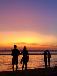 Silhouette people on beach against sky during sunset