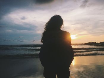 Silhouette woman standing at beach during sunset