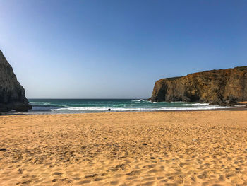 Scenic view of beach against clear blue sky