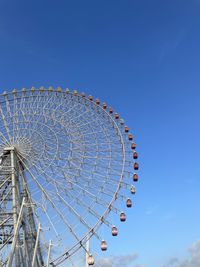 Low angle view of ferris wheel against blue sky