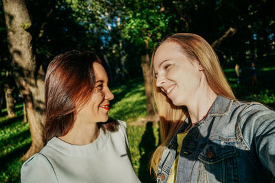 Portrait of smiling friends standing against trees