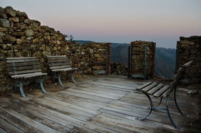 Empty chairs on landscape against clear sky