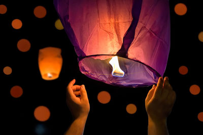 Cropped image of person holding lantern at night
