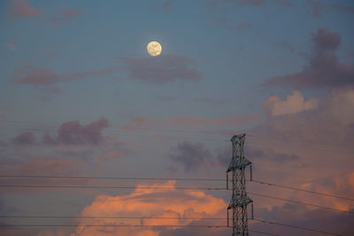 Low angle view of silhouette electricity pylon against sky during sunset