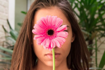 Close-up of woman holding pink gerbera daisy