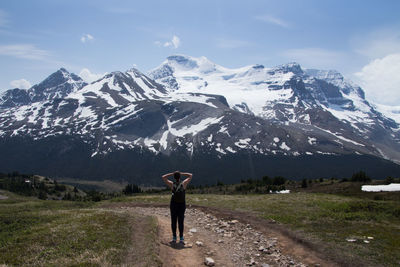 Woman standing on snowcapped mountain against sky
