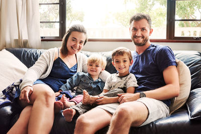 Portrait of happy family sitting on sofa at home