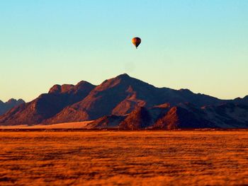 Hot air balloon flying over mountains against clear sky
