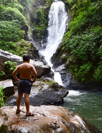 Rear view of woman standing against waterfall