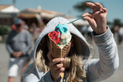 Woman holding ice cream in city during sunny day