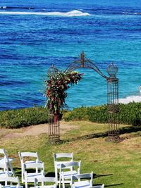 Chairs and table on beach by sea against sky