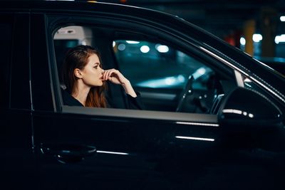 Side view of young woman sitting in car
