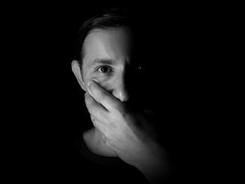 Portrait of young man against black background