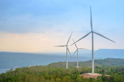 Wind turbines on landscape against sky
