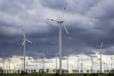 Low angle view of windmills against sky
