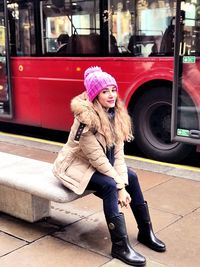Full length of young woman sitting on street