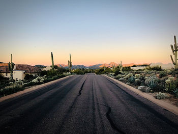 Road by city against clear sky during sunset