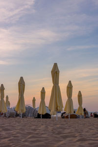 People on beach against sky during sunset