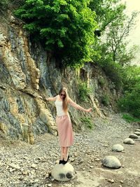 Young woman with arms outstretched standing on rock